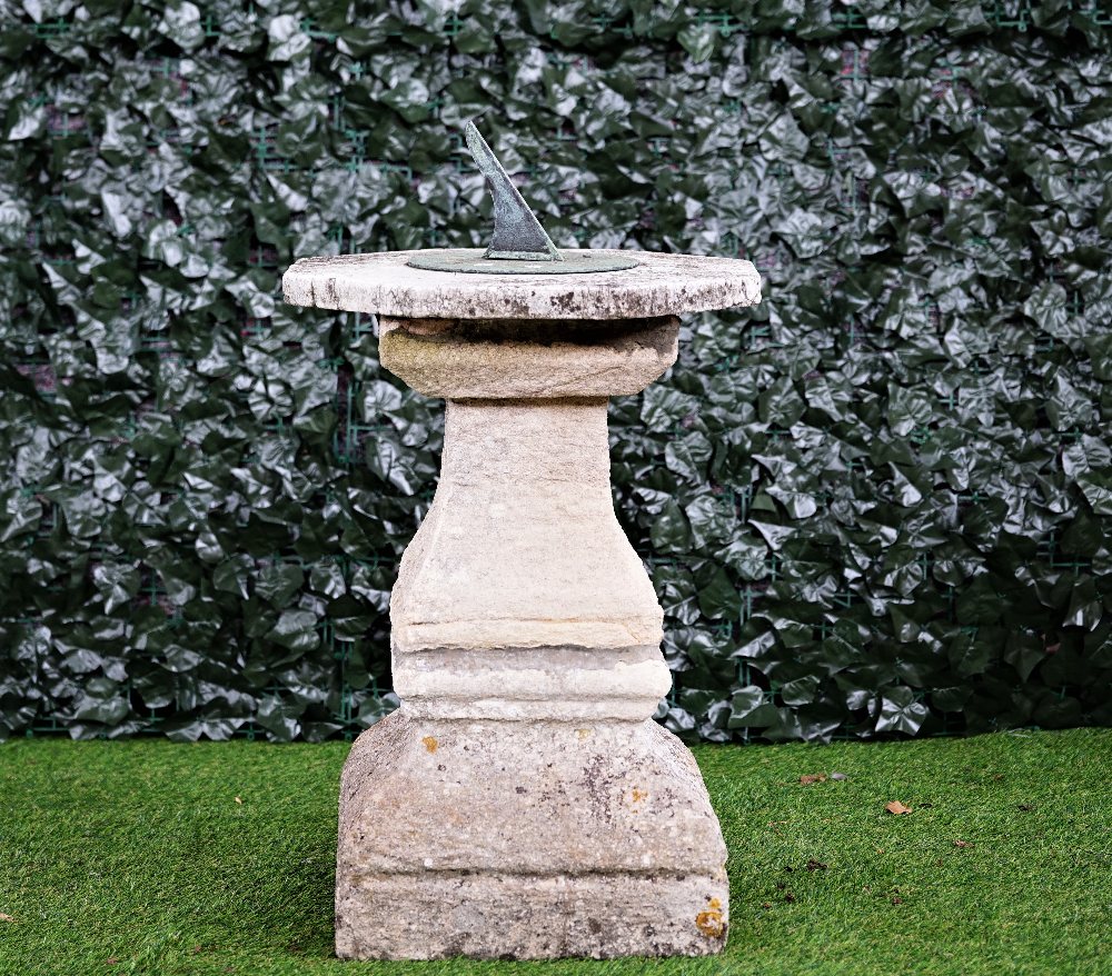 A cast bronzed sundial on a stone square baluster column,
