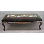 An Empire style parcel gilt ebonised rectangular footstool on scroll supports,