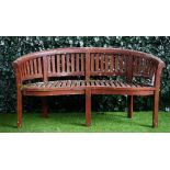 A teak curved garden bench of slatted construction, 160cm wide x 84cm high.