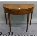 A George III mahogany demi-lune foldover card table on tapering square supports,