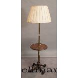 A combination brass and mahogany standard lamp occasional table, on a cast metal paw foot base,
