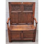 A 18th century oak box seat settle, with carved panel back and open arms, 96cm wide x 128cm high.