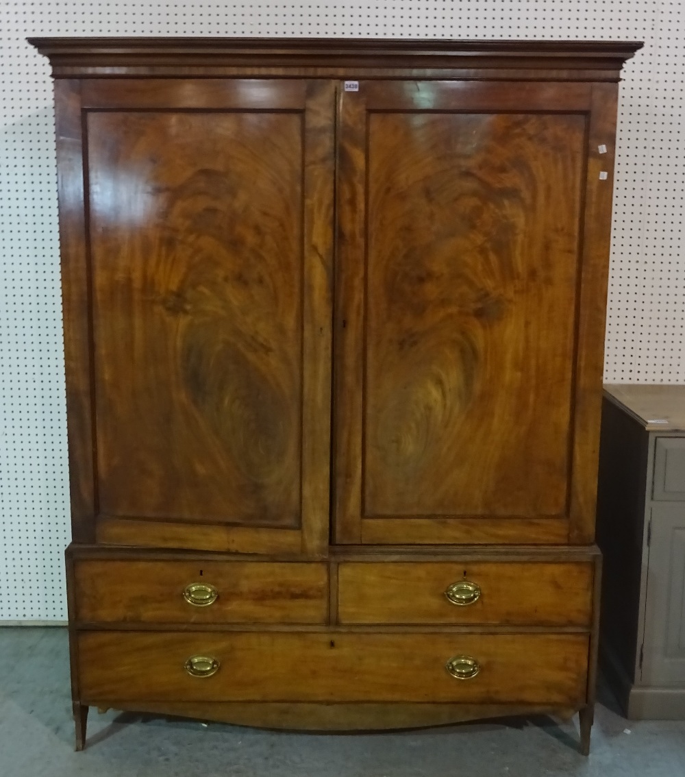 A George III mahogany linen press with moulded cupboard doors over two short and one long drawer,