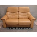 A contemporary two-seater reclining sofa, in tan leather, 128cm wide.