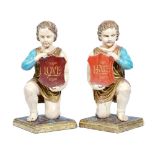 A pair of painted figures of kneeling cherubs,