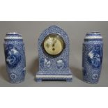 A 20th century blue and white ceramic clock garniture with a pair of cylindrical vases 27cm high