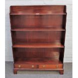A George III style mahogany floor standing four tier waterfall bookcase on bracket feet,