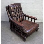 A mahogany open arm easy chair, with button back brown leather upholstery, on turned supports,