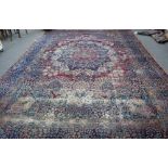 A Kerman carpet, Persian, the madder field with a bold rosette medallion, indigo spandrels,