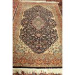 An Indian rug of Persian design, the dark indigo field with a pale medallion, ivory spandrels,