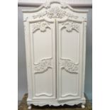 A pair of Louis XVI style white painted arch topped armoires with carved foliate decoration on