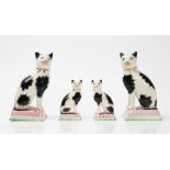 Two pairs of Staffordshire pottery cats, 20th century, each black and white a