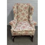 A 19th century Queen Anne style shaped wingback armchair, on turned mahogany supports,