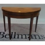 A George III mahogany demi-lune foldover card table on tapering square supports,