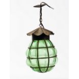 An Arts and Crafts green glass and metal caged lantern, suspended from a chain, 38cm high.