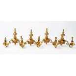 A set of four 20th century gilt metal twin branch wall lights, with flame finials,