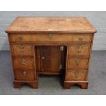 A Queen Anne walnut veneered chequer banded kneehole desk,