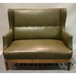 An early 20th century oak framed wingback two seater sofa on reeded tapering supports,