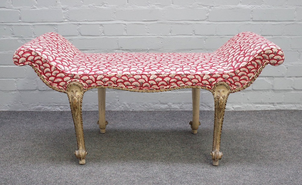 A George III style window seat, with outswept arms on four cream painted scroll supports,