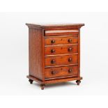 A miniature mahogany chest with a cushion drawer over four long graduated drawers on bun feet,