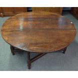 A large 17th century oak gate leg dining table with opposing frieze drawers on baluster supports