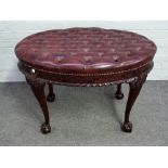 An 18th century style footstool, the oval leather upholstered top over carved frieze,