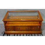A modern yew wood rectangular coffee table with inset glass top over three drawers on a plinth base,