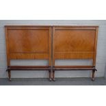 A pair of late 19th century, early 20th century satinwood single beds with concave footboards,