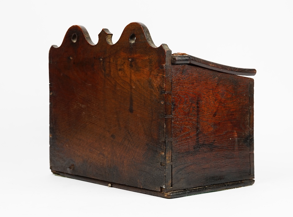 A George III oak candle box, the pierced and shaped back over a sloped front, 38cm wide x 31cm long.