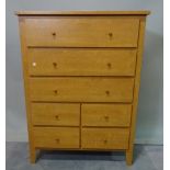 A modern hardwood tall chest with mirrored back over three long and four short drawers,