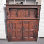 A 17th century oak court cupboard with two pairs of panelled cupboards flanked by turned columns,