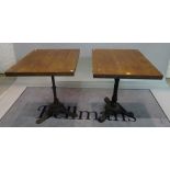 A pair of modern hardwood square occasional tables on cast iron bases, 60cm wide x 74cm high, (2).