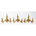 A set of six 20th century gilt metal twin branch wall lights, with flame finials,