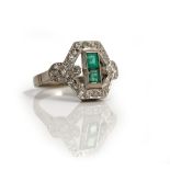 An emerald and diamond dress ring of plaque design, channel set with two rectangular cut emeralds,