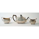 A silver three piece tea set, comprising; a teapot with black fittings,