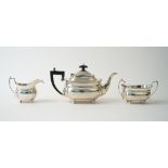 A silver three piece tea set, comprising; a teapot with black fittings,