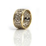 A two colour gold and diamond set band ring, in a wide white gold pierced openwork Celtic design,