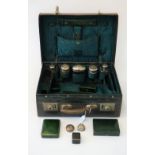 A late Victorian leather toilet case containing five silver topped faceted glass bottles and jars,