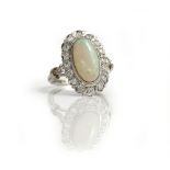A white gold, opal and diamond set oval cluster ring, collet set with the oval opal at the centre,