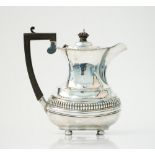 A silver hot water jug, decorated with a fluted band to the body and raised on bun feet,
