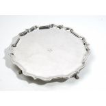 A silver salver, of shaped circular form, in the Chippendale style, raised on four pad feet,