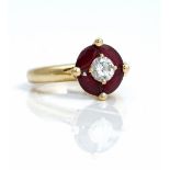 A French diamond and ruby ring, claw set with a circular cut diamond at the centre,