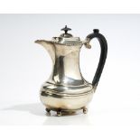 A silver hot water jug of waisted form, decorated with a gadrooned rim,