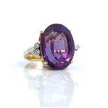 A gold, amethyst and diamond ring, claw set with the large oval cut amethyst at the centre,