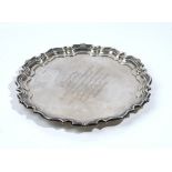 A silver salver, of shaped circular form, having a Chippendale style rim, raised on three feet,