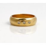 An 18ct gold and diamond set band ring, gypsy set with a row of three circular cut diamonds,