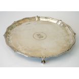 A silver shaped circular salver, engraved with a shield to the centre, decorated with a beaded rim,