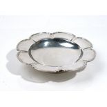A silver dish, of shaped circular form, having a panelled rim, raised on a circular foot,