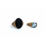 A gold and oval black onyx signet style ring, having scroll decorated shoulders,