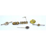 A gold brooch, collet set with a row of four oval cut citrines, a citrine two stone brooch,